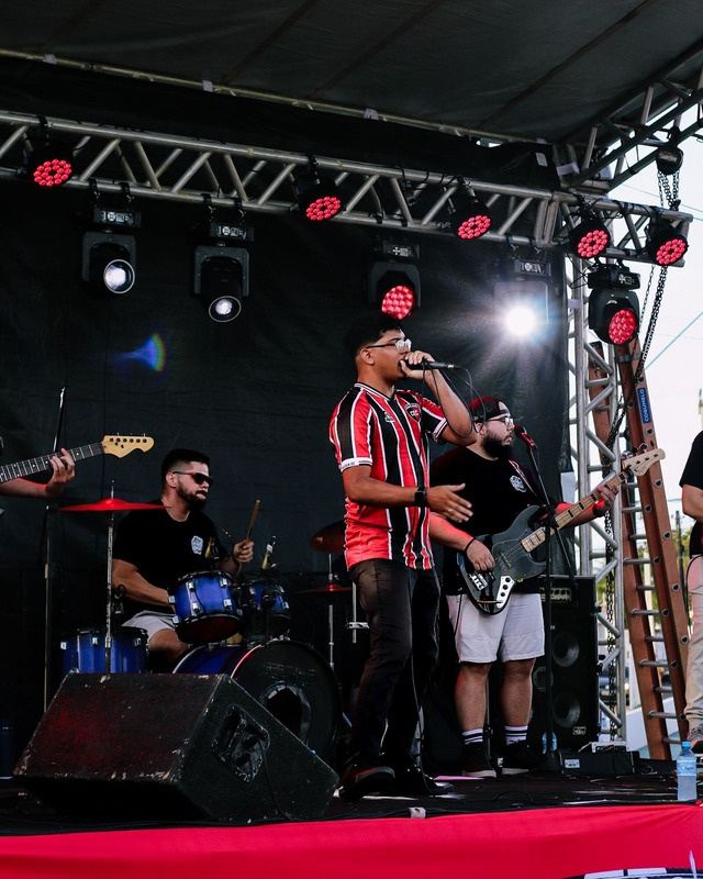 Banda tocando no palco com iluminação vermelha