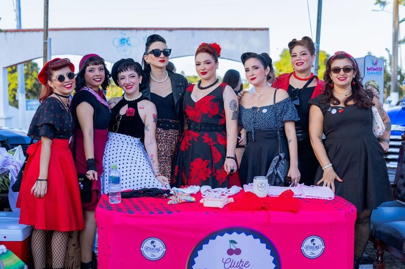 Grupo de mulheres com roupas retrô posando em uma mesa decorada